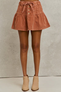 Brown corduroy skirt worn by a person on a neutral background