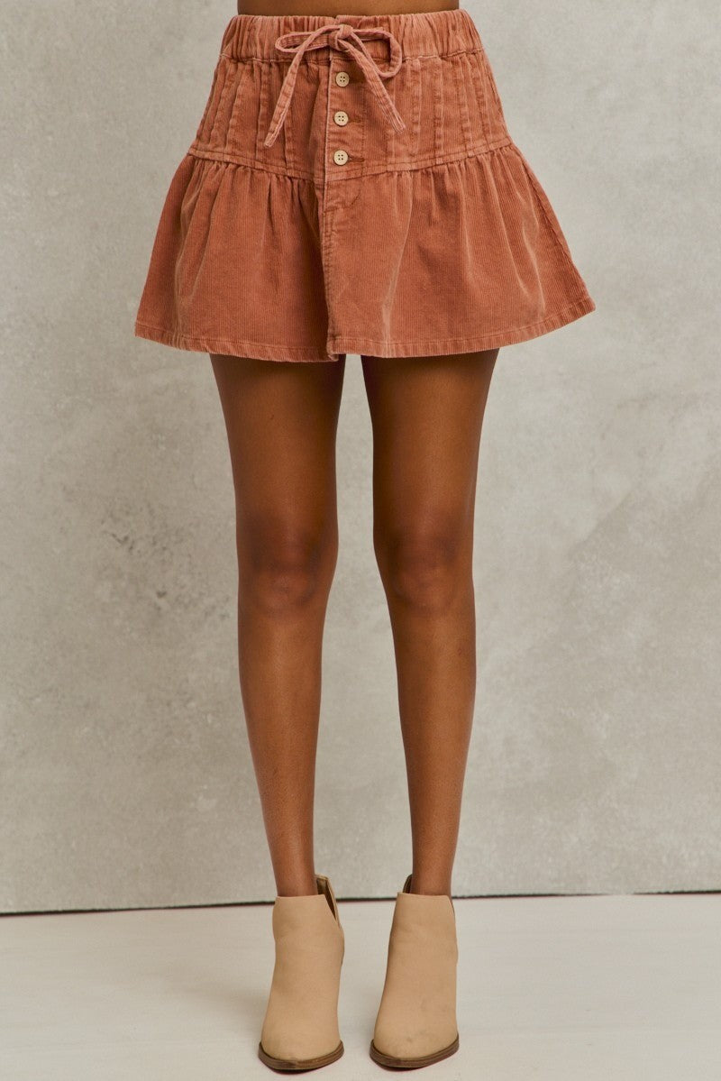 Brown corduroy skirt worn by a person on a neutral background