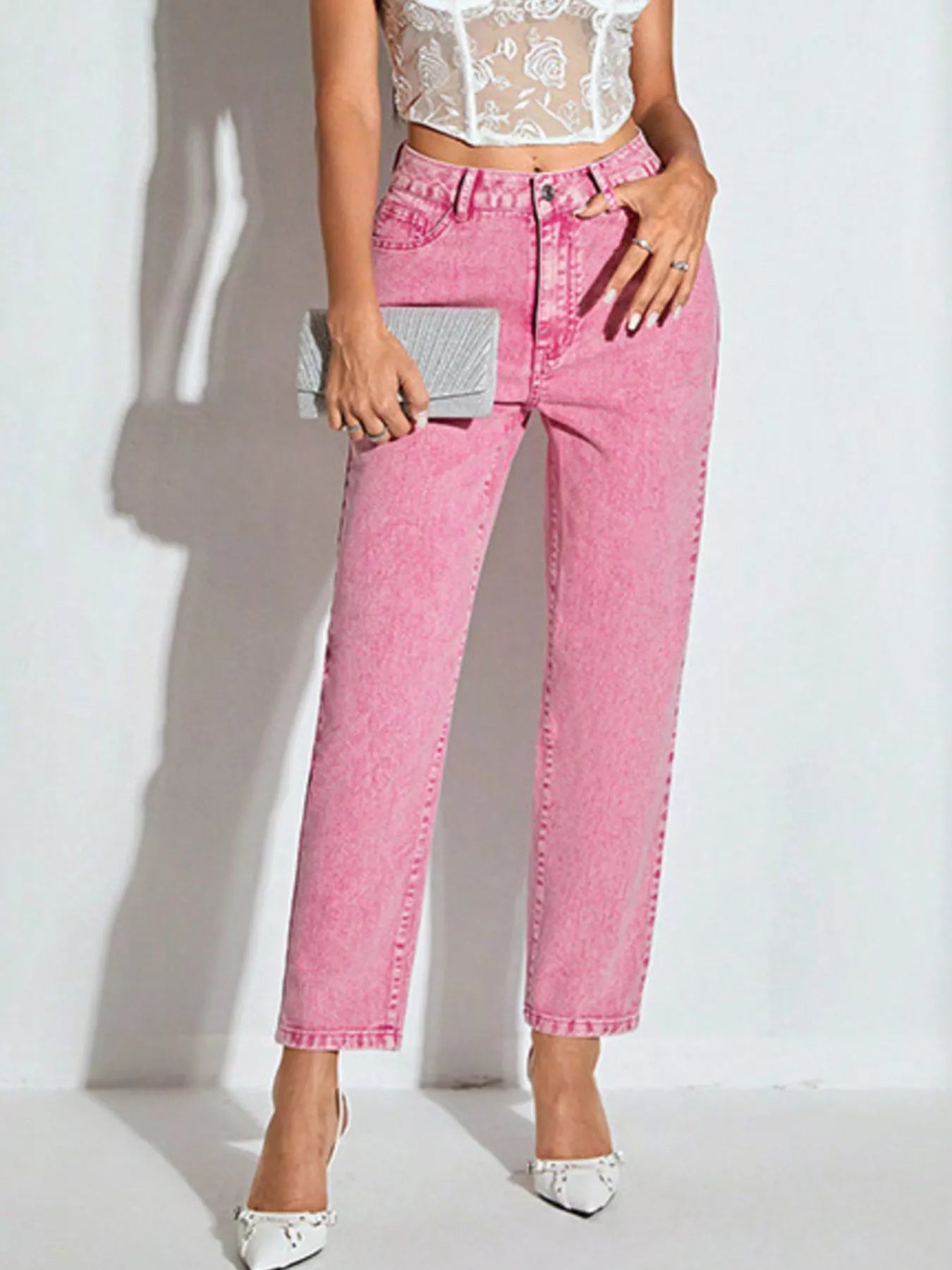 Person wearing pink jeans and a white lace top against a plain background