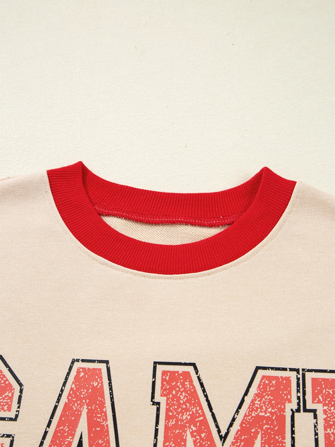 Close-up of a shirt with red collar and text on a beige background