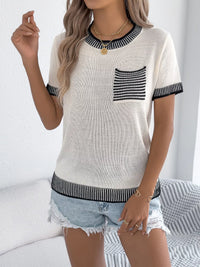 Woman wearing a white and black striped sweater with a pocket, standing against a white background.