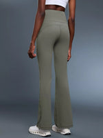Person wearing olive green flared pants on a gray background
