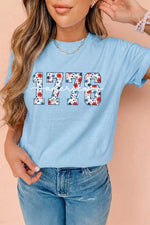 Person wearing a light blue t-shirt with '1776' printed on it, standing against a beige background.