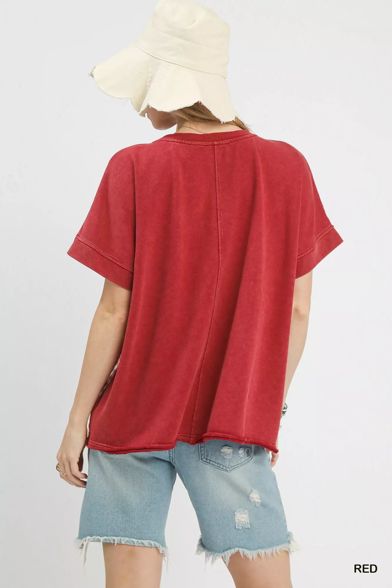 Person wearing a red t-shirt and denim shorts on a white background