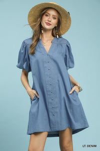 Woman wearing a light blue dress with puff sleeves and a straw hat against a light blue background