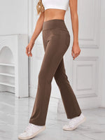 Person wearing brown flared pants and white sneakers in a minimalistic setting
