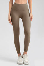 Person wearing brown leggings on a plain background