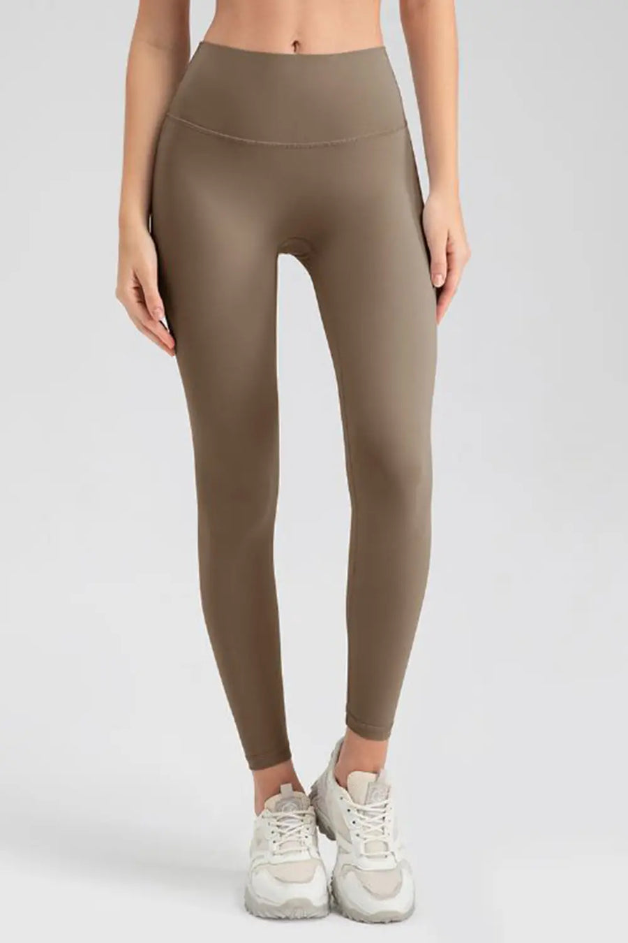 Person wearing brown leggings on a plain background