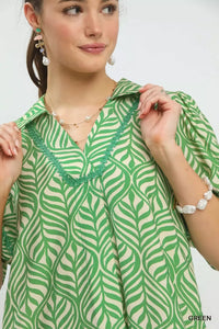 Woman wearing a green and white patterned blouse with a plain background