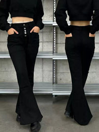 Two reflections of a person wearing black flared pants and a black cropped top in a metallic surface.