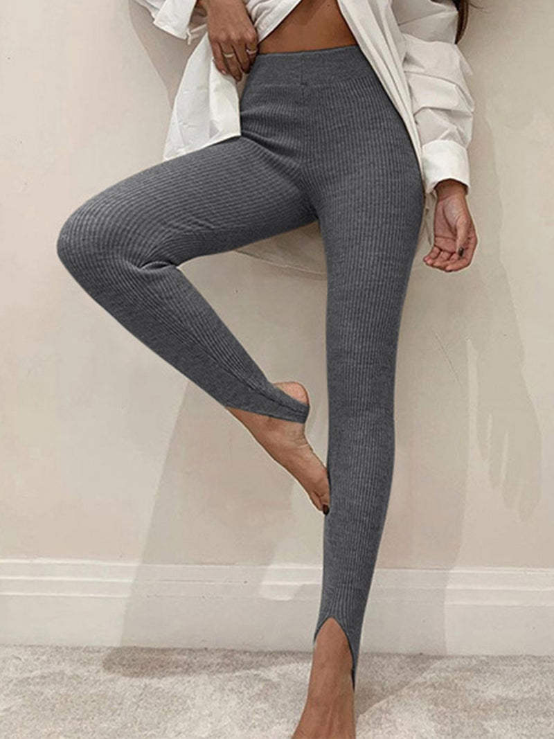Person wearing gray leggings with a white shirt in a minimal indoor setting