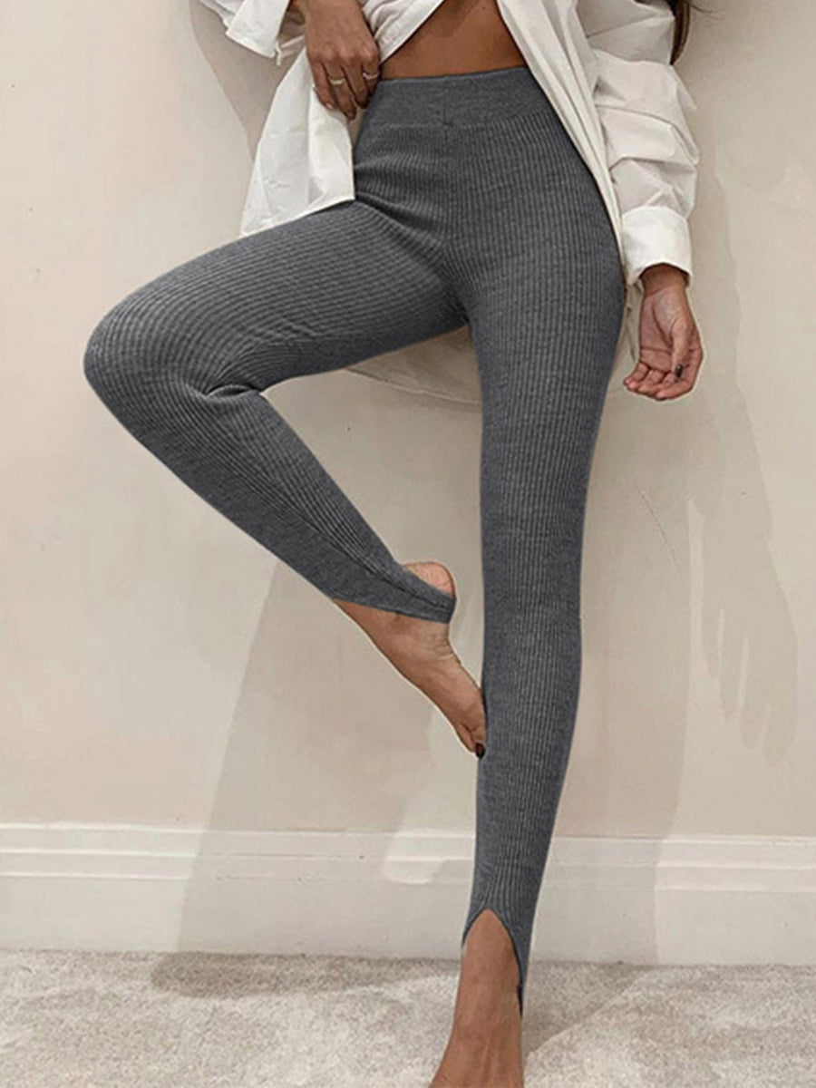 Person wearing gray leggings with a white shirt in a minimal indoor setting