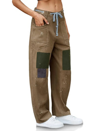 Brown cargo pants with green patches worn by a person on a white background