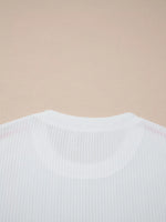 Close-up of a white ribbed sweater on a beige background