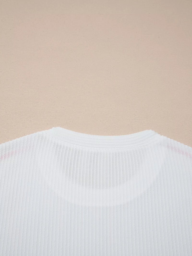Close-up of a white ribbed sweater on a beige background