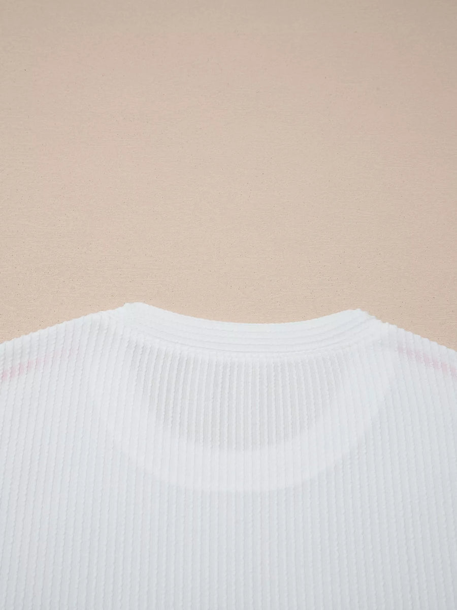Close-up of a white ribbed sweater on a beige background