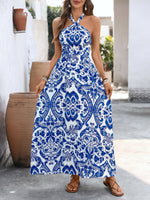 Woman wearing a blue and white patterned halter neck dress outdoors.