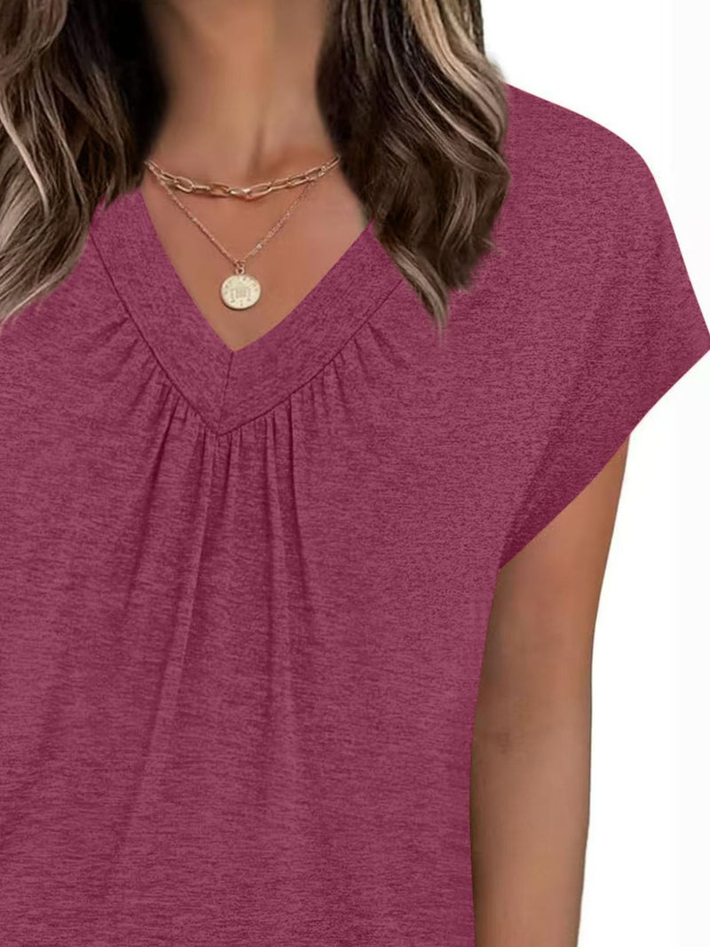 Close-up of a person wearing a maroon top with a V-neckline on a white background