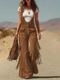 Woman wearing brown fringed overalls and white top in a desert setting