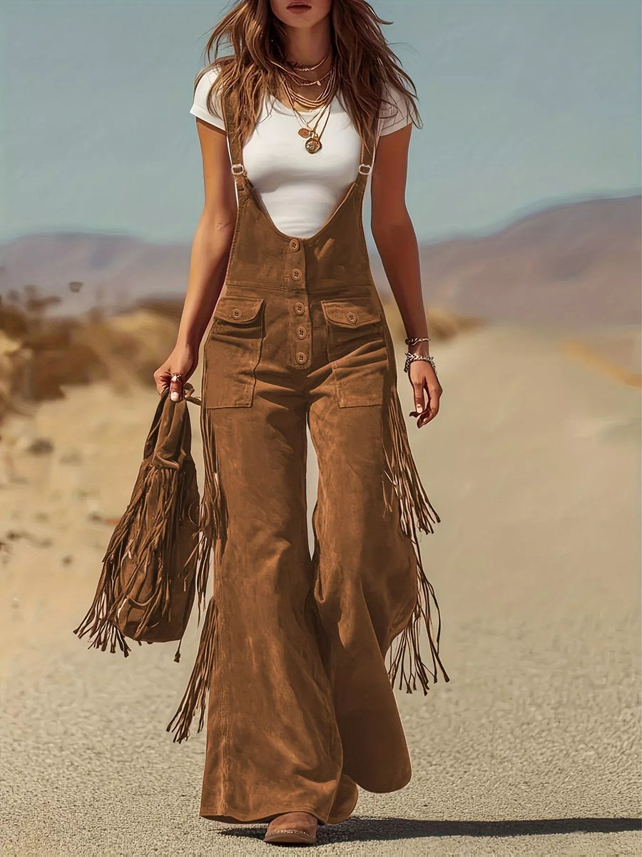 Woman wearing brown fringed overalls and white top in a desert setting