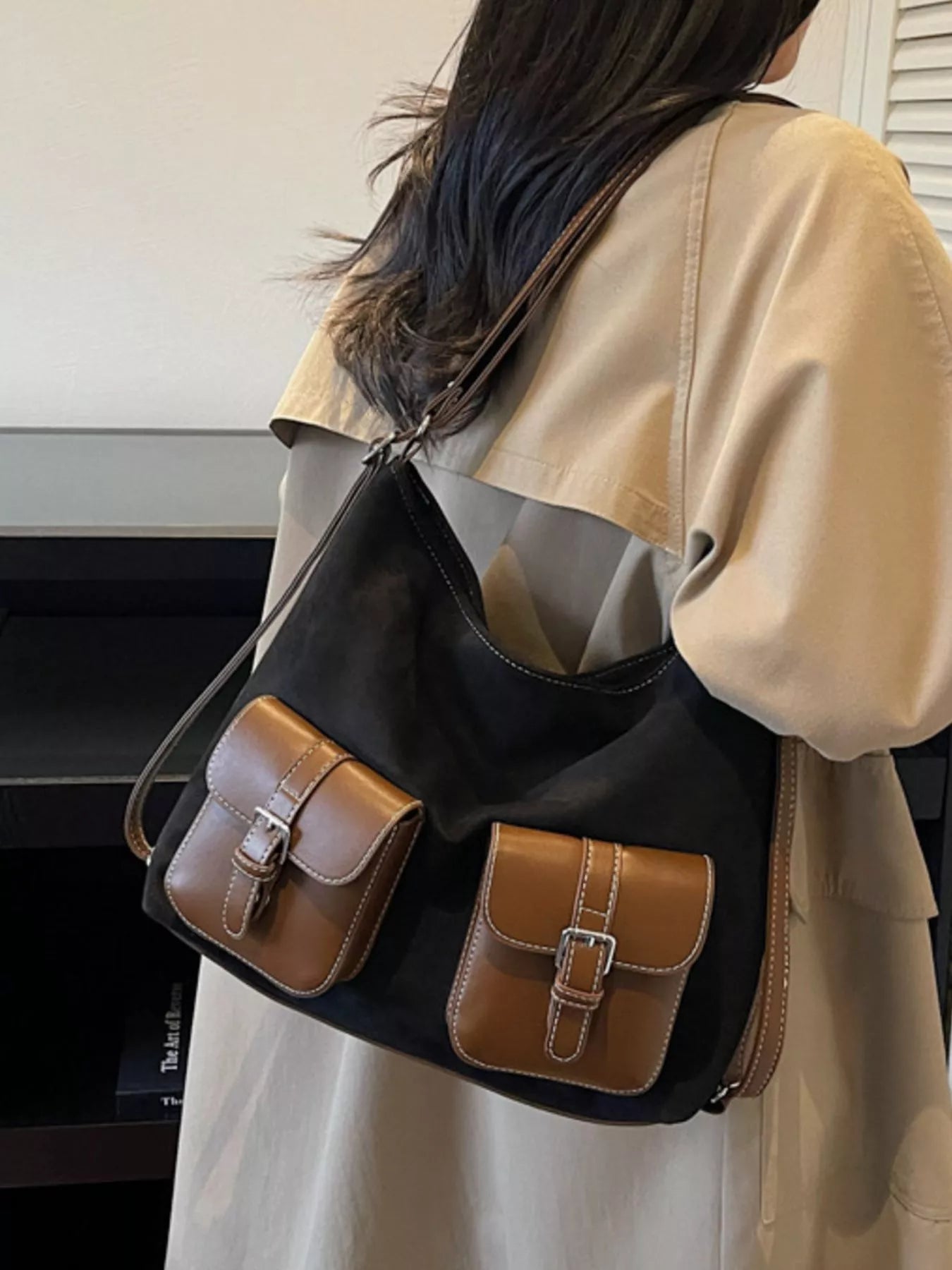 Person wearing a black and brown handbag with a neutral background