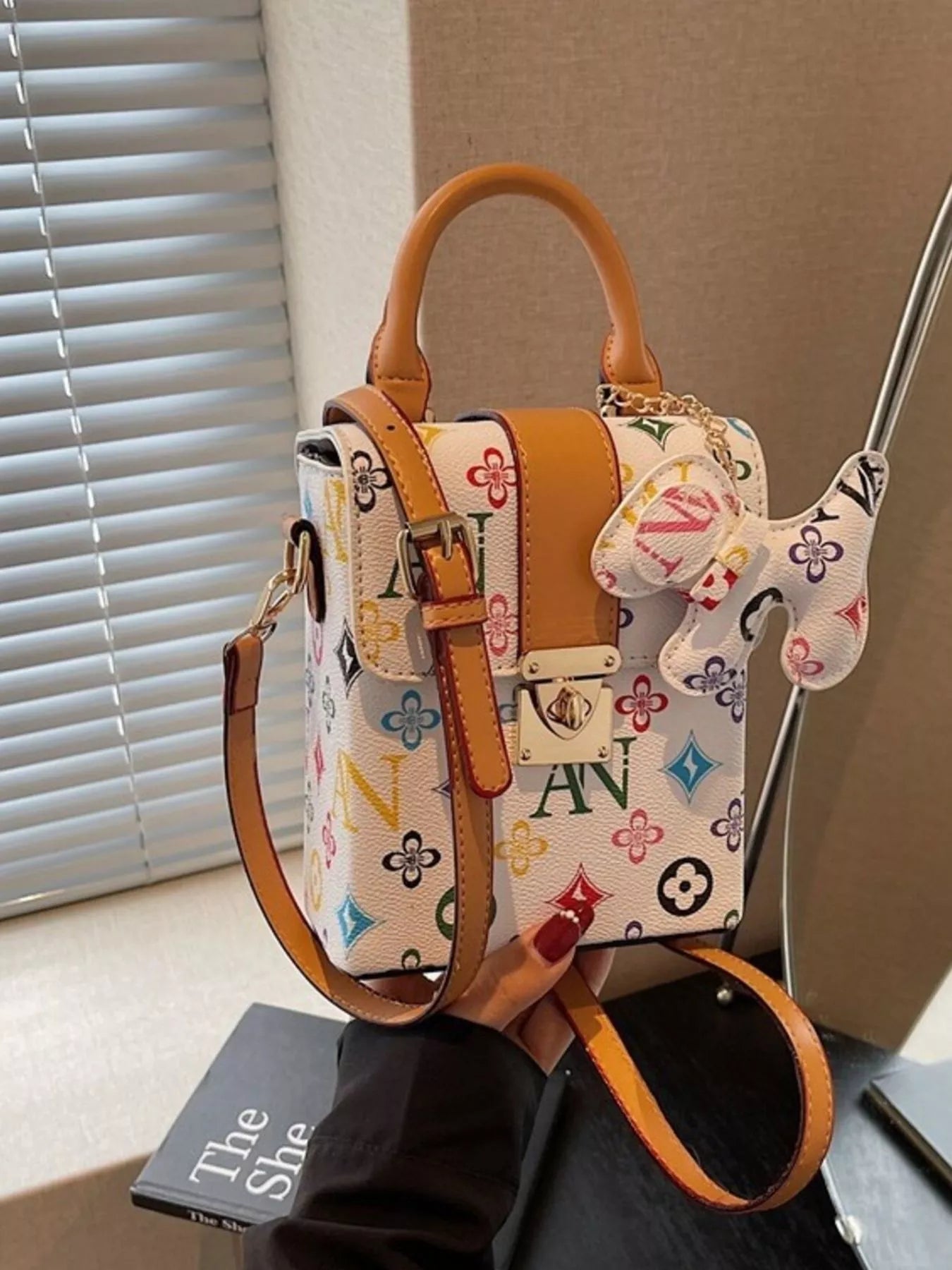 Designer handbag with colorful pattern and bow detail on a neutral background