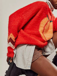 Person wearing a red sweater with orange patterns on a neutral background