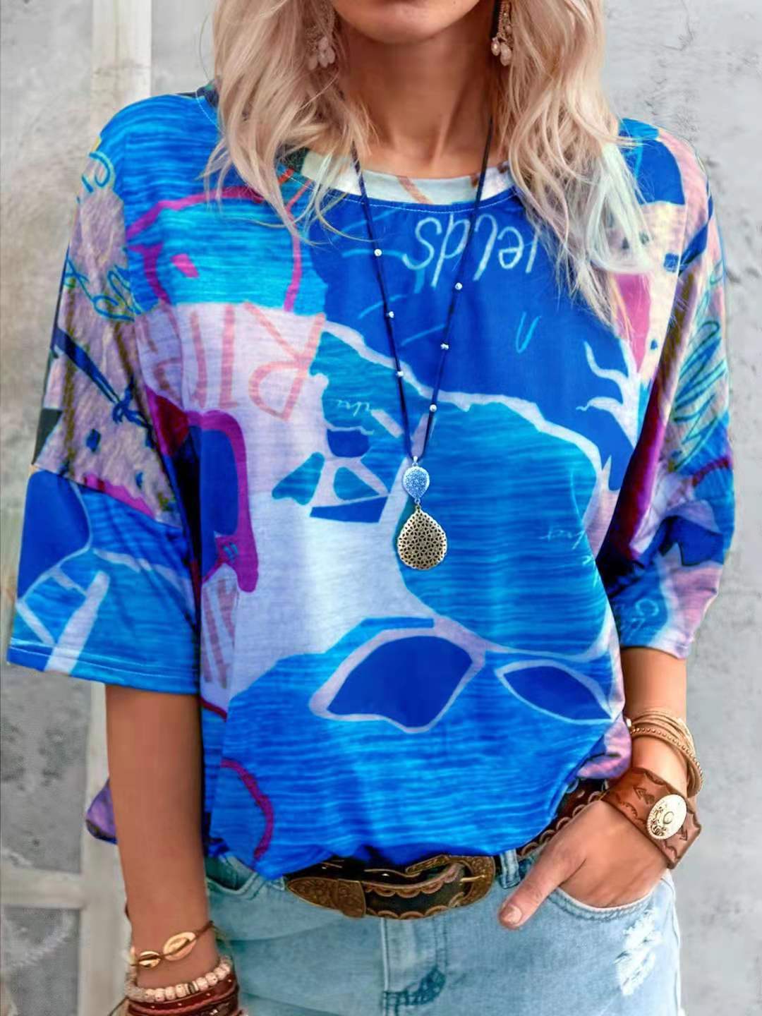Person wearing a colorful abstract-patterned shirt with a necklace and bracelets.