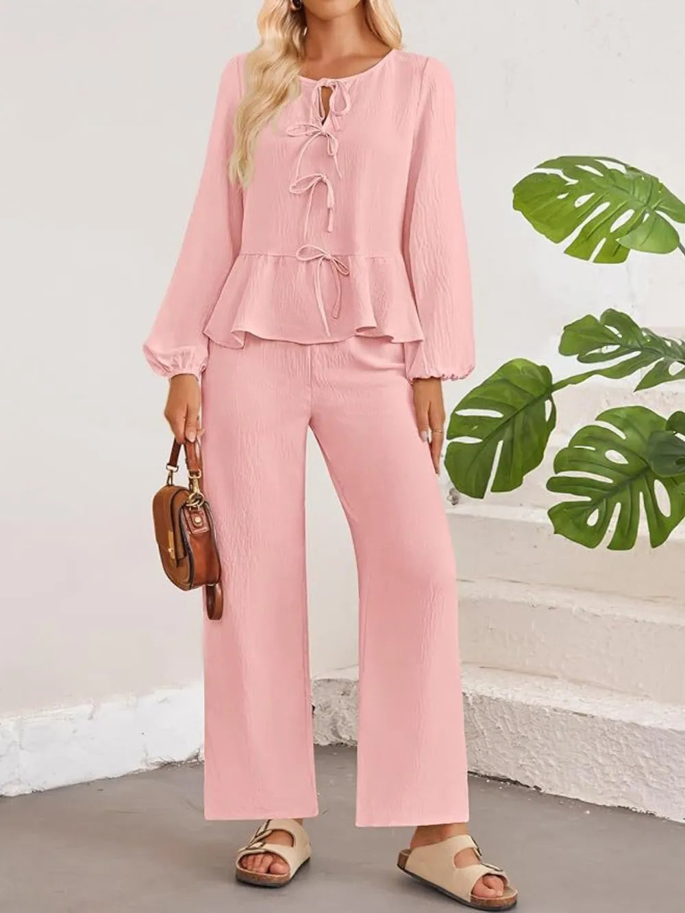 Woman wearing a pink outfit with a plain background and green leaves.