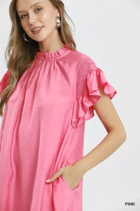 Woman wearing a pink dress with ruffled sleeves on a white background