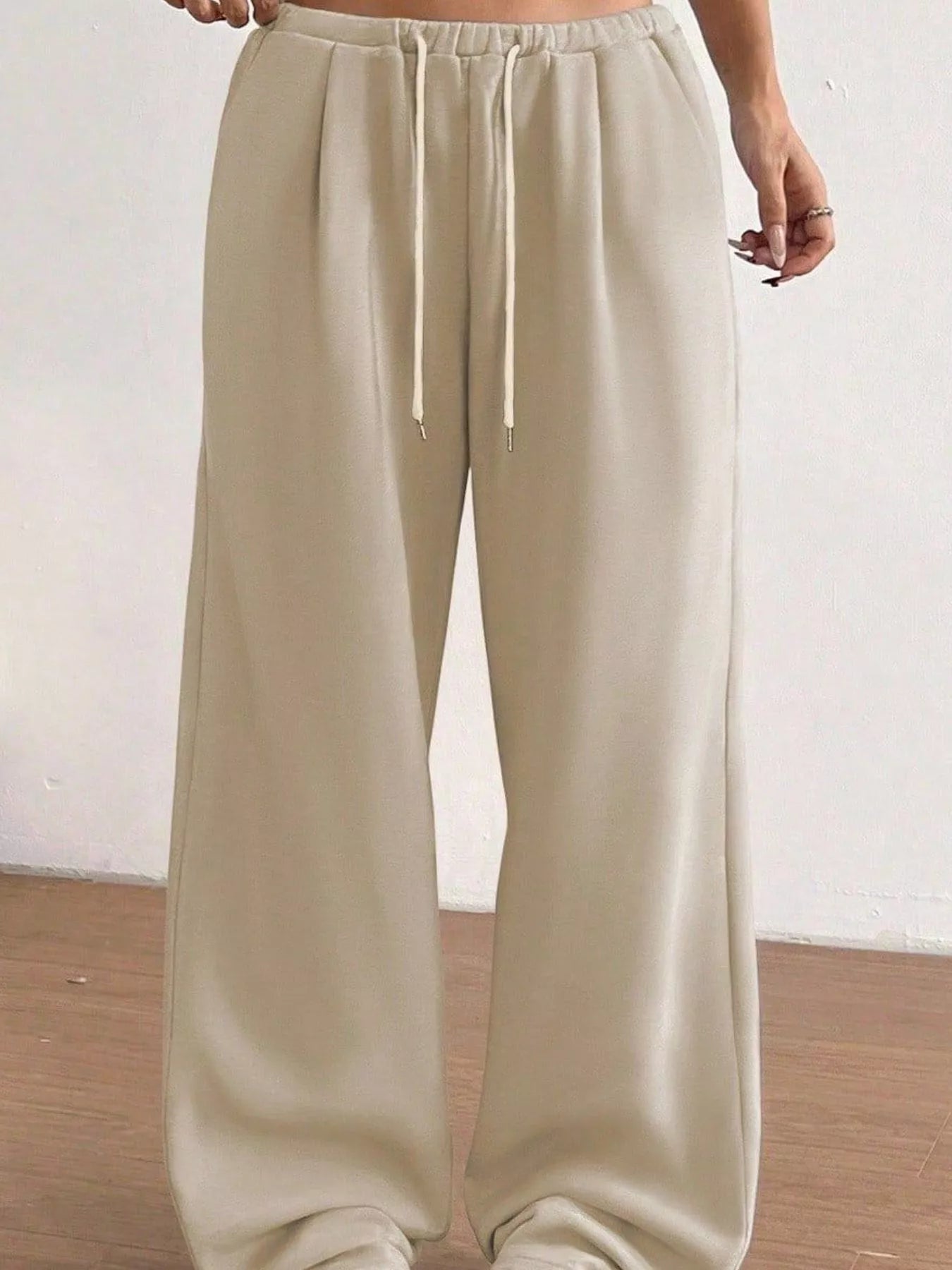 Beige wide-leg pants with a drawstring waist on a plain background