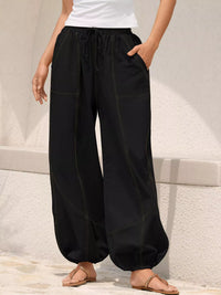 Person wearing black wide-leg pants with a white background