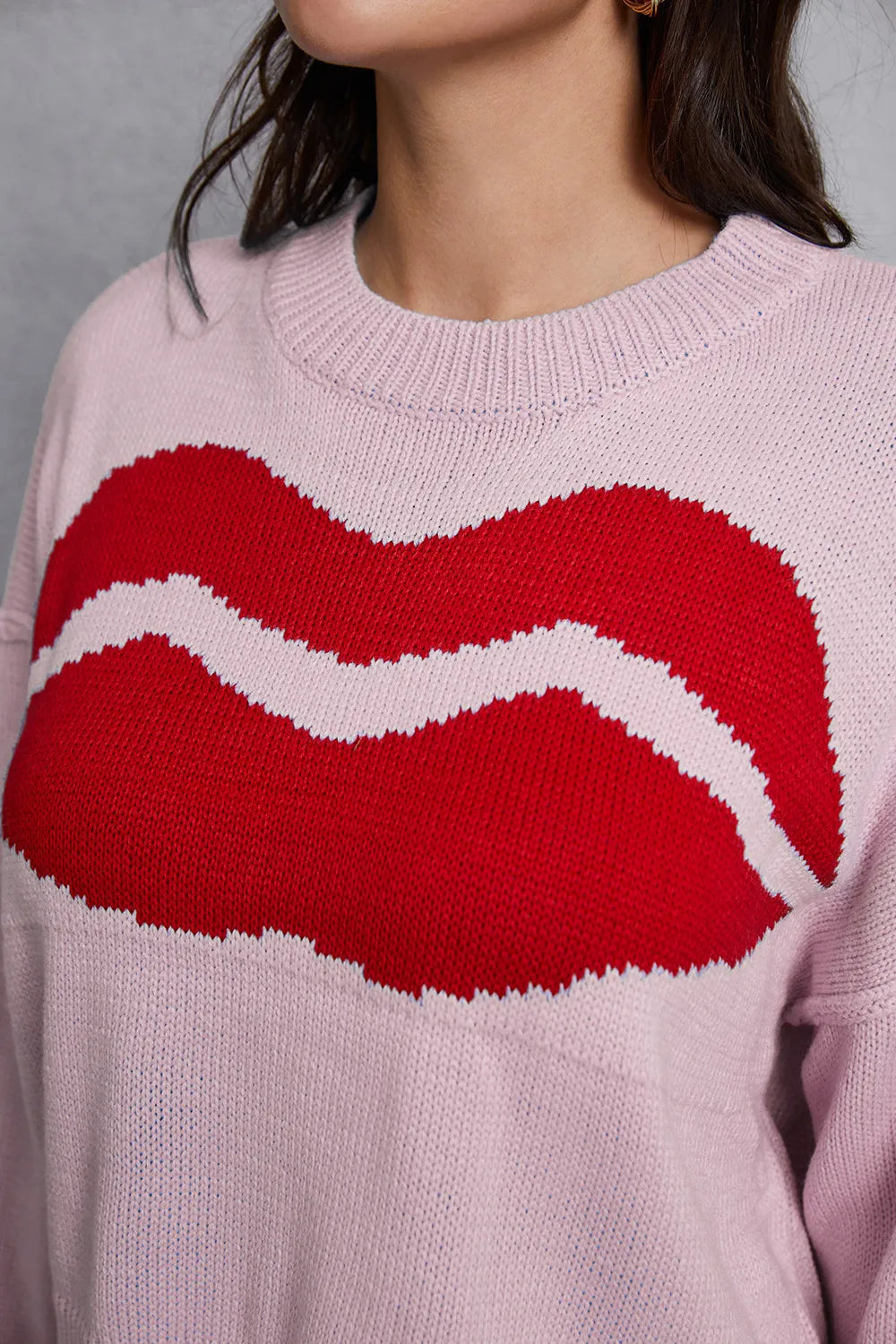 Pink sweater with red and white lip design worn by a person
