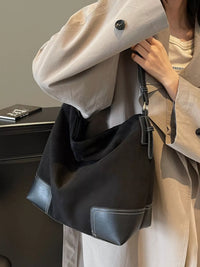 Person holding a black handbag with a neutral background