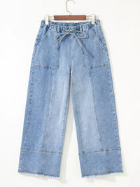 Blue denim pants on a hanger against a white background