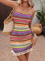 Woman wearing a colorful patterned dress holding a woven bag outdoors.
