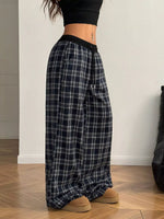 Person wearing plaid pants and black top on a wooden floor.