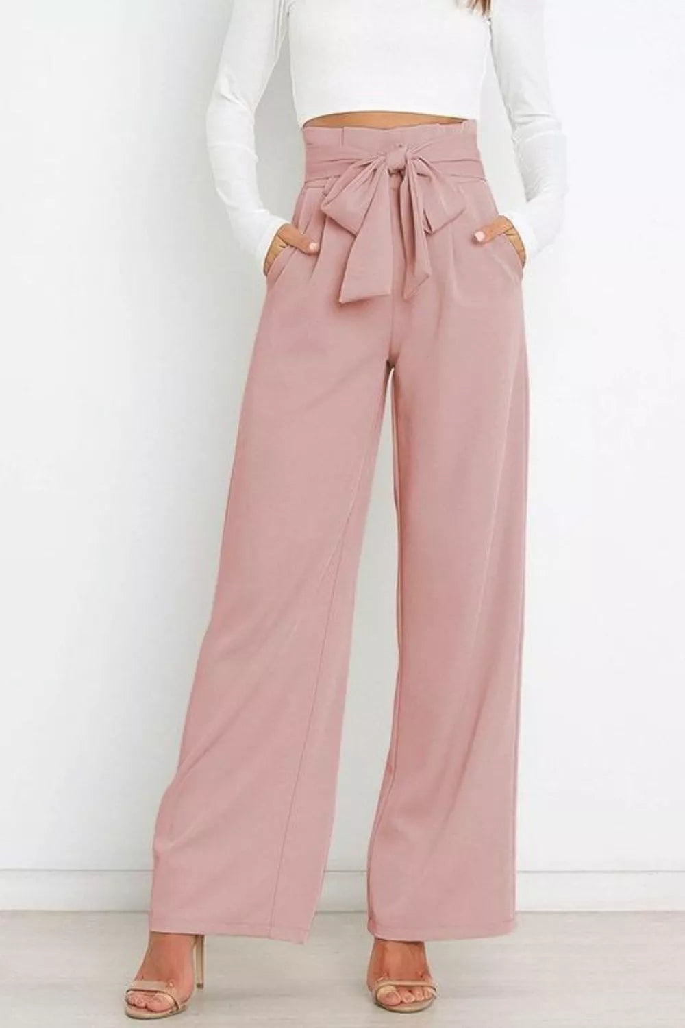 Pink wide-leg pants with a tie waist worn by a person on a white background