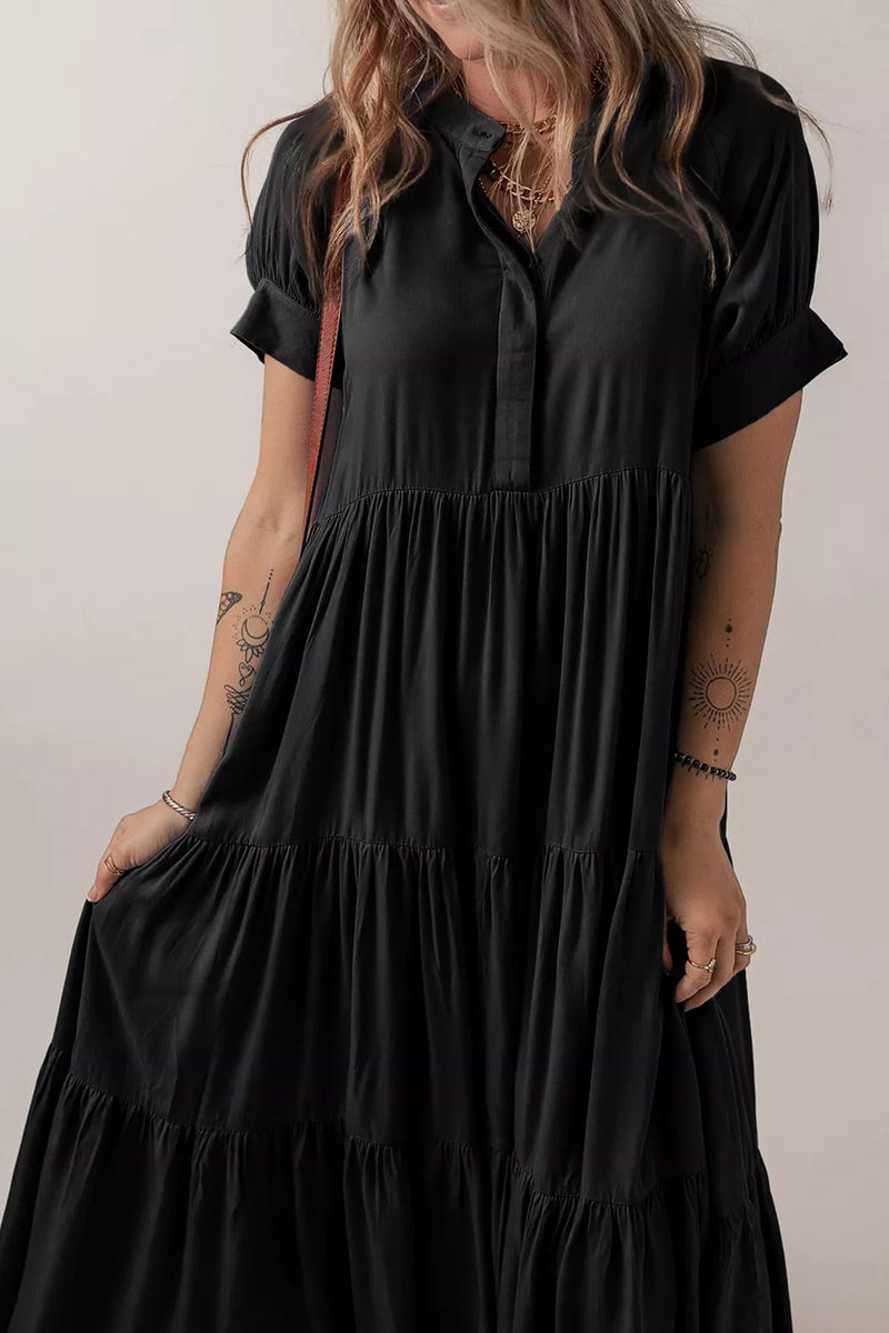 Person wearing a black dress with short sleeves against a neutral background