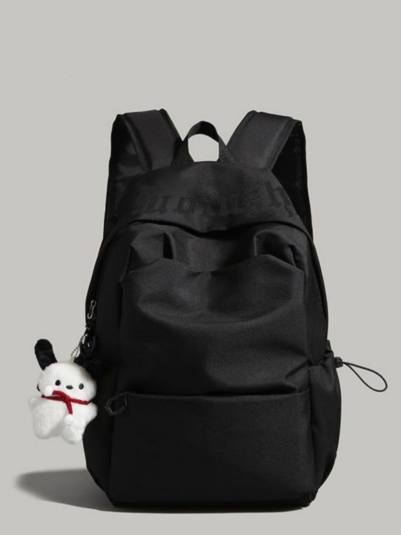 Black backpack with a small white plush toy attached on a gray background