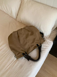 Brown bag on a bed with white pillows
