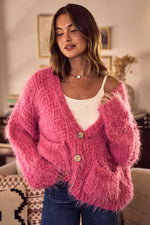 Woman wearing a pink fuzzy cardigan in a cozy indoor setting