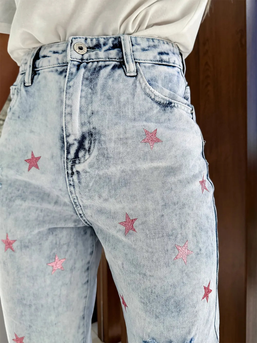 Light blue jeans with pink stars on a wooden background