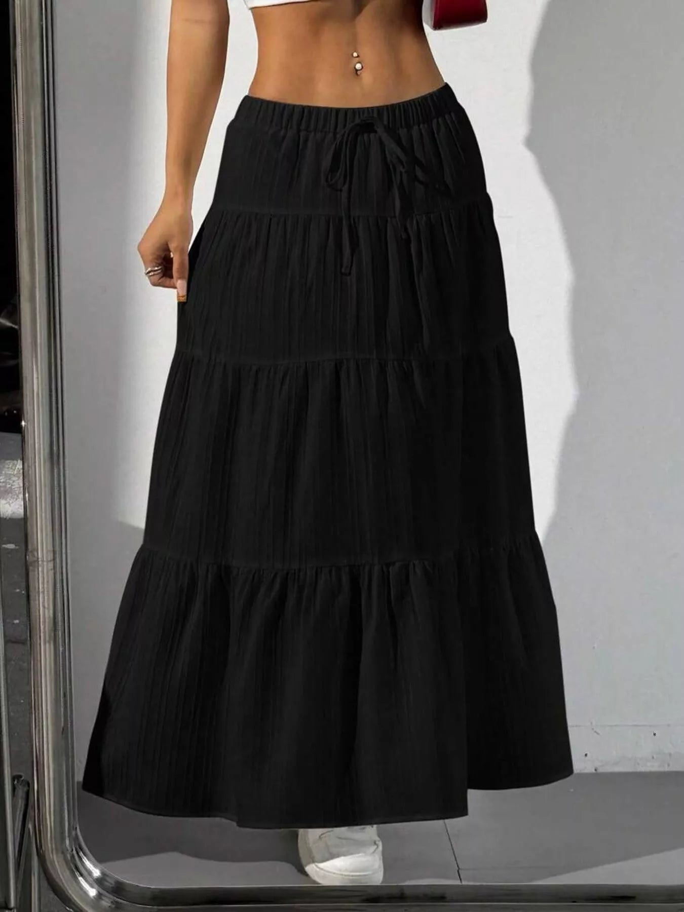 Black tiered skirt worn by a person on a white background
