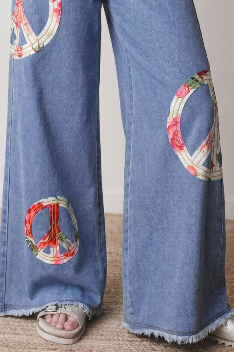 Blue jeans with peace symbol patches on a neutral background