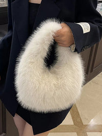 White fluffy handbag held by a person wearing a dark coat.