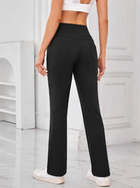 Person wearing black high-waisted pants in a minimalistic setting