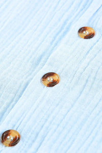 Three tortoiseshell button earrings on a light blue textured fabric background