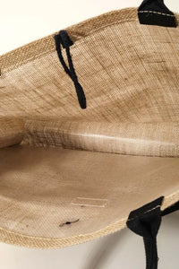 Close-up of a jute bag with black straps on a white background