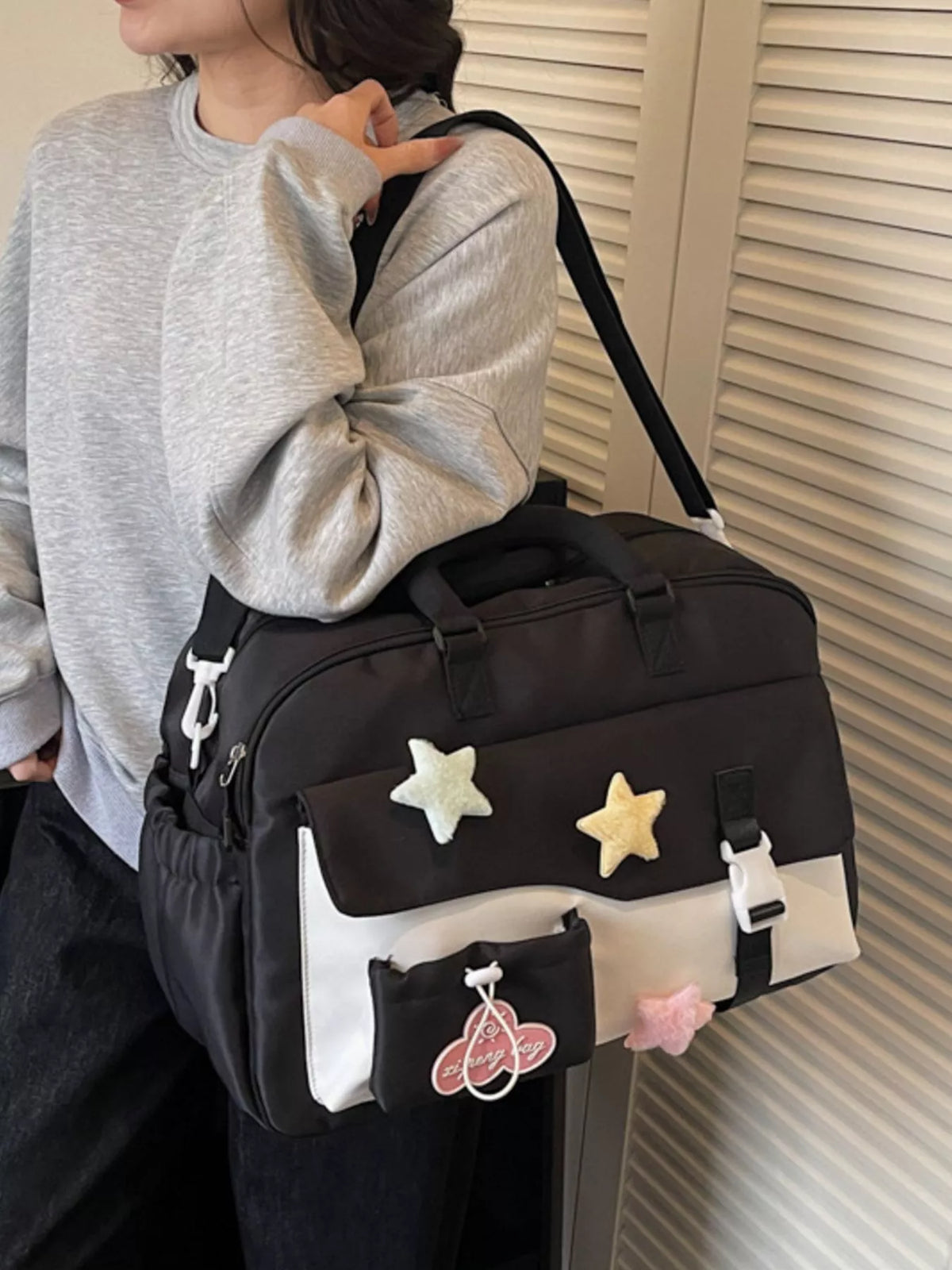 Person holding a black duffel bag with star and cartoon character designs.